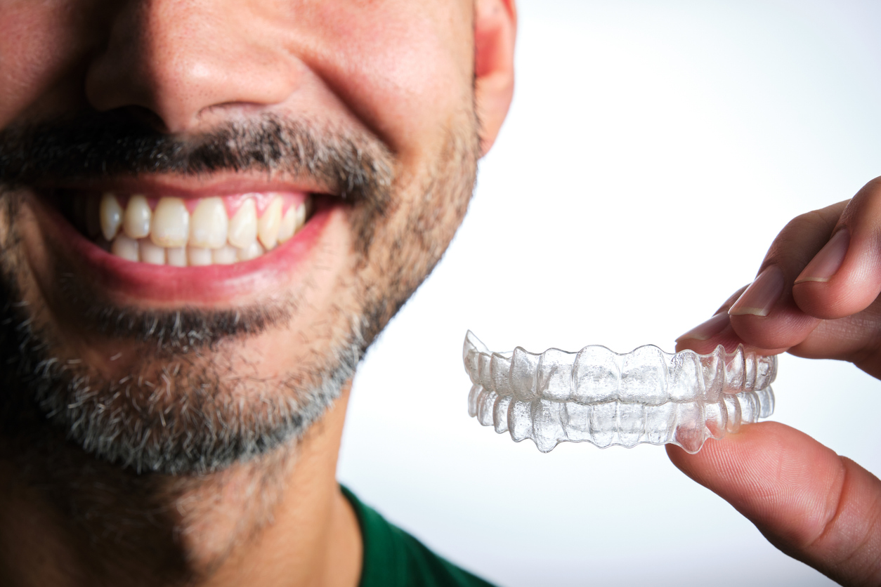unrecognizable dark-haired man with beard putting on transparent dental retainer unrecognizable dark-haired man with beard putting on transparent dental retainer