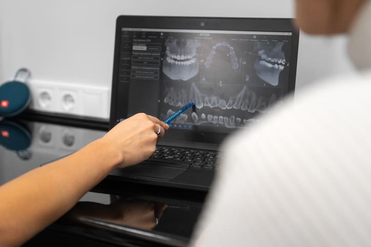 Dentist shows a 3D image of the jaw to the patient on a laptop screen. Modern technologies of dentistry Dentist shows a 3D image of the jaw to the patient on a laptop screen. Modern technologies of dentistry